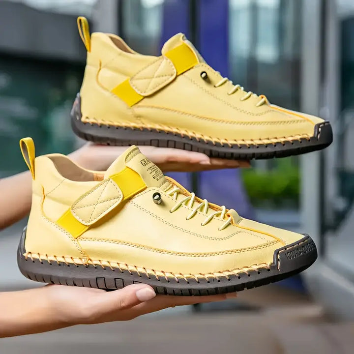 Clementine yellow orthopaedic sneakers held up by hand, side profile pair